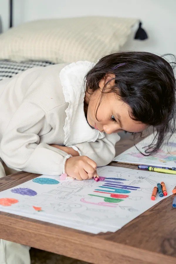 Little girl coloring with crayons at a table